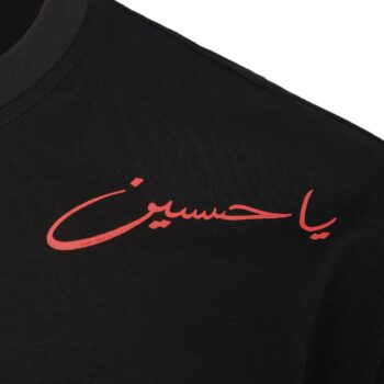 Close-up of Ya Hussein II T-shirt featuring red Arabic “يا حسين” shoulder artwork on black oversized fabric